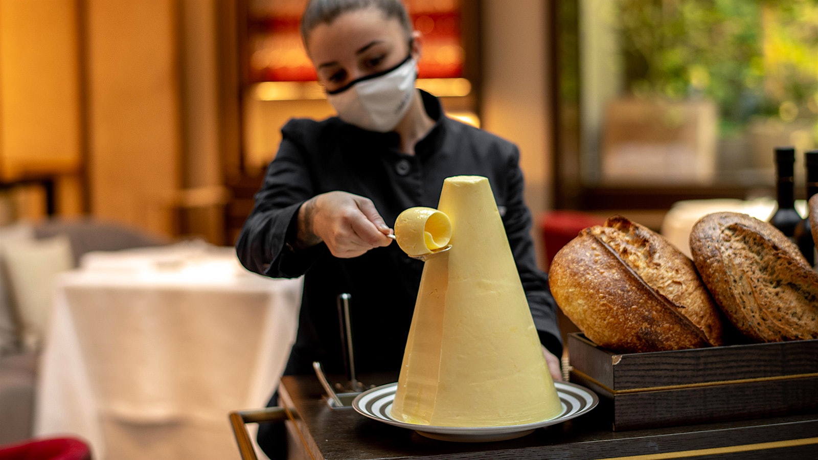 A server presents a selection of cheeses in a cart